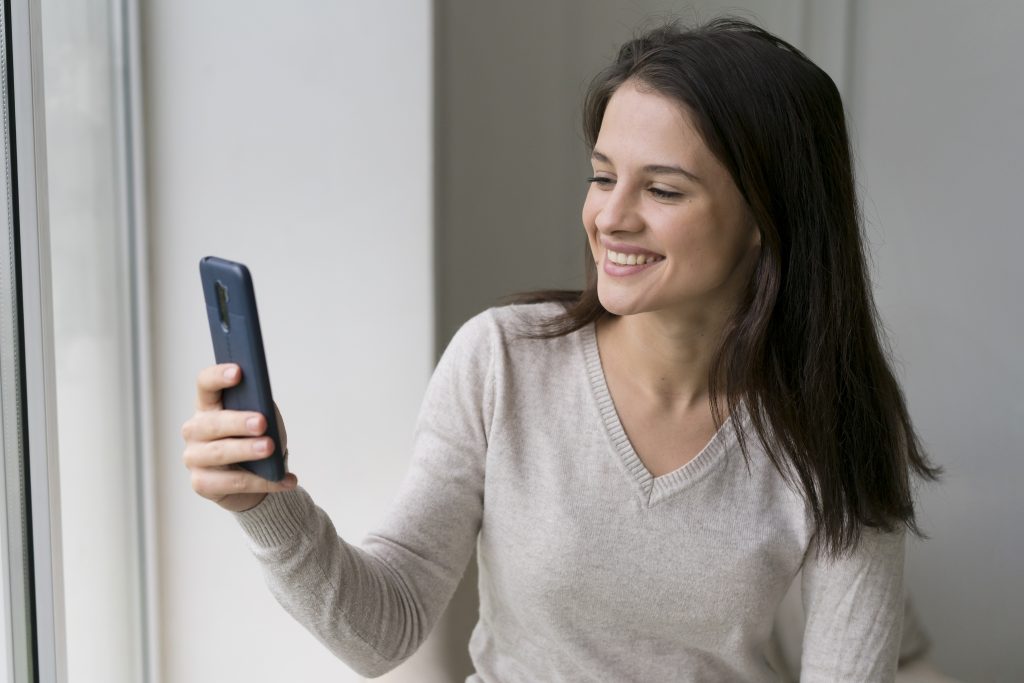 Mulher com celular na mão registrando o controle de ponto pelo celular